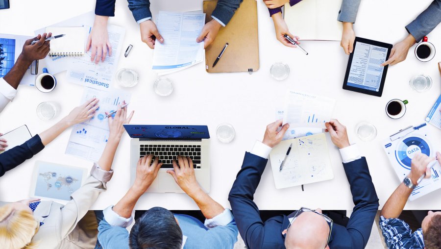 an aerial view of an office table with laptops and people's hands visible